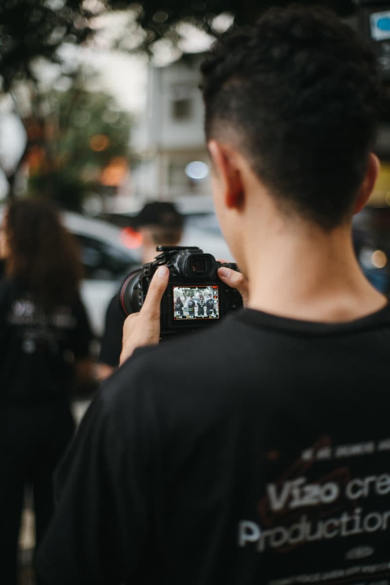 Retrato de um jovem de cabelo escuro e curto, de blusa preta, diante de um fundo claro liso.